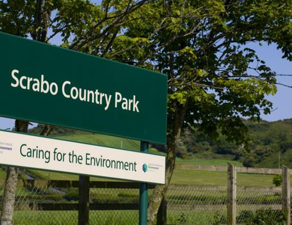 Image of the NIEA signpost entitled Scrabo County Park, caring for the environment with Scrabo Tower in background