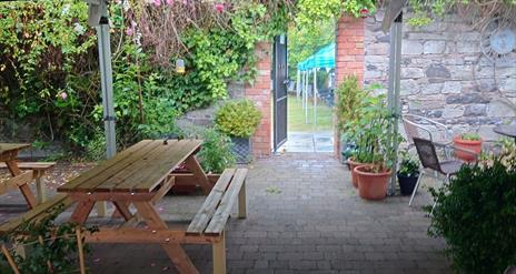 Exterior of No. 14 Georgian House Comber, looking from Courtyard into the Walled Garden, with picnic benches and shrubbery in view