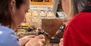 Two Ladies Melting Down Some Silver Using Two Torches