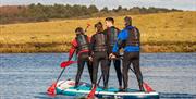 Four people standing up on a Paddleboard