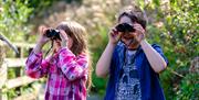 Two children looking through binoculars.